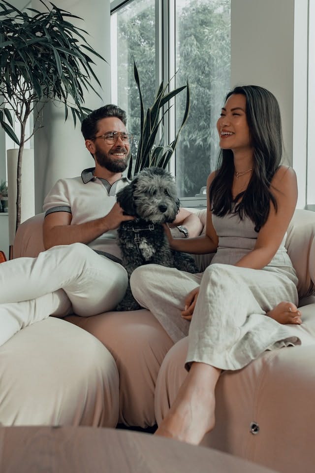 Un homme et une femme sur un sofa avec un chien, heureux de faire affaire avec Wiseday pour leur hypothèque.